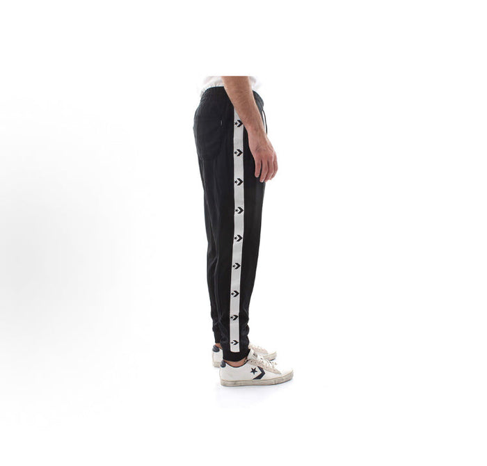 Black track pants with white side stripe and tapered leg opening, with sneakers