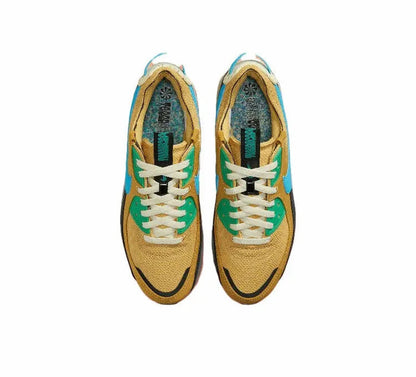 Nike Air Max 90 shoe in wheat gold with white laces, teal lining, and blue-green accents