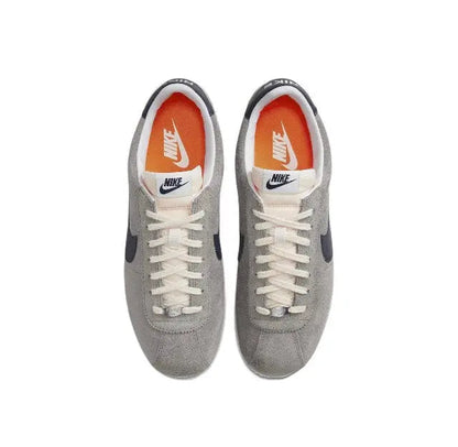 Grey Nike Cortez lace-up sneakers with orange-tinted tongue and white swoosh