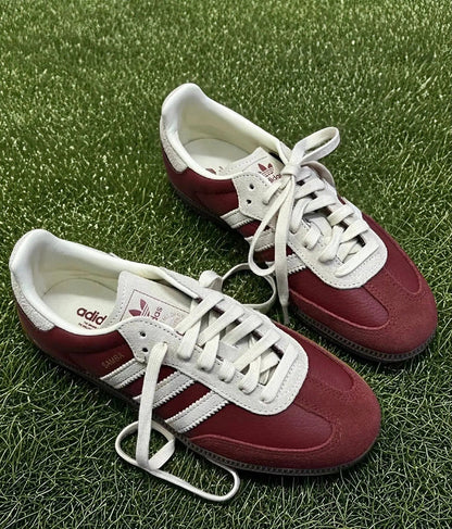 Adidas Samba OG sneakers on grass, burgundy uppers with white laces and 3-Stripes